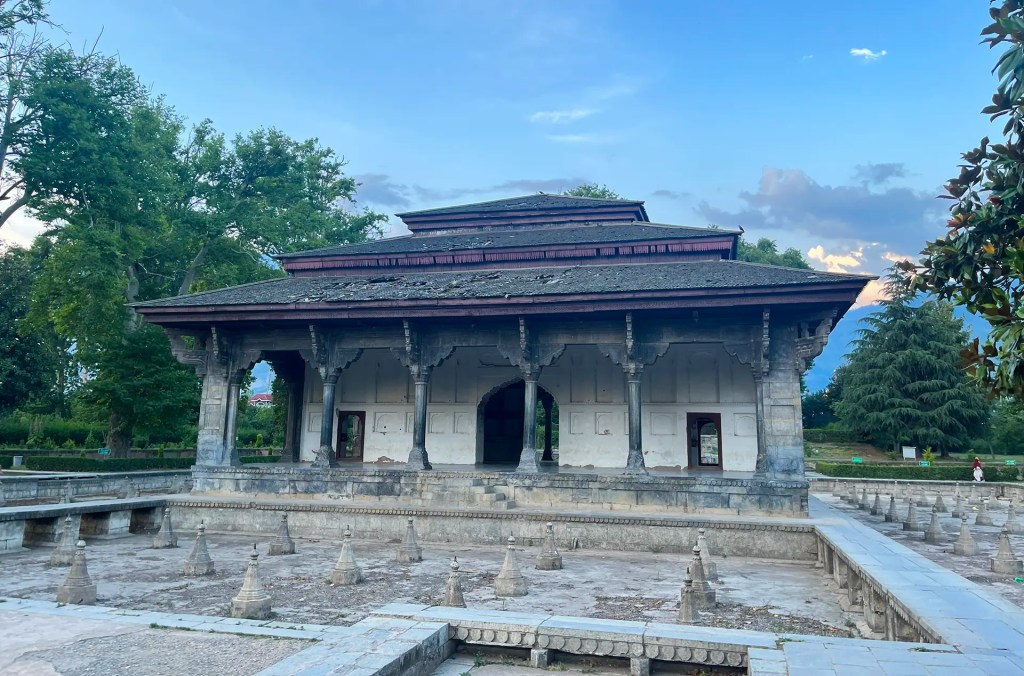 Mughal architecture pavilion at Shalimar Bagh in Srinagar, Kashmir, featuring arched corridors, carved stonework, and flowing water channels.